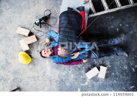 Colleague performing CPR on an injured worker lying on the ground after accident. Concept of occupational safety and health in workplace. 114939801