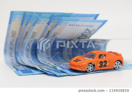 Toy car on the background of banknotes, purchase, insurance and the cost of car ownership. Toy car on the background of banknotes, purchase, insurance and the cost of car ownership. 114939859
