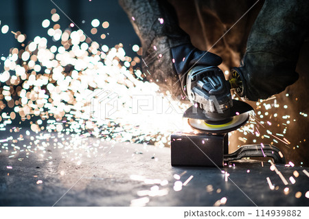 Close up of work of welder in workshop, operating welding machine, wearing protective clothing and a welding mask. Close up of work of welder in workshop, operating welding machine, wearing protective clothing and a welding mask. 114939882