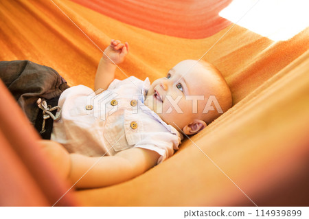 The baby is lying in a rocking hammock during a warm summer day. The baby is lying in a rocking hammock during a warm summer day. 114939899