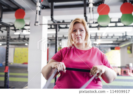 Portrait of overweight woman exercising in gym. Portrait of overweight woman exercising in gym. 114939917