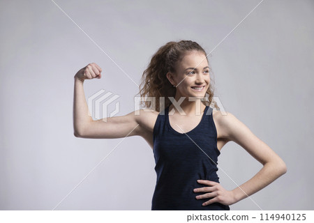 Portrait of a gorgeous fitness girl with curly hair, flexing muscles. Studio shot, white background with copy space 114940125