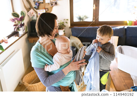 Young son helping mother with hosehold chores, hanging clothes on drying rack. Weekly chores, weekend activities. Young son helping mother with hosehold chores, hanging clothes on drying rack. Weekly chores, weekend activities. 114940192