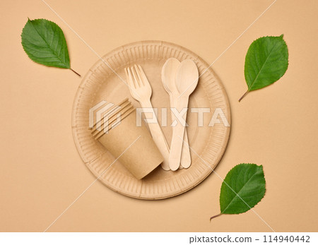 Paper cups, wooden spoons and forks on a beige background Paper cups, wooden spoons and forks on a beige background 114940442