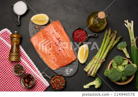 Raw piece of trout on a black board and spices Raw piece of trout on a black board and spices 114940578
