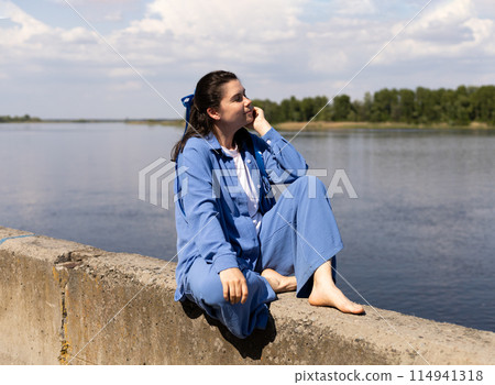 young woman with a blue bench sits on the seashore young woman with a blue bench sits on the seashore 114941318