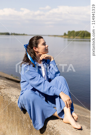 young woman with a blue bench sits on the seashore, conceived, dreamed young woman with a blue bench sits on the seashore, conceived, dreamed 114941319