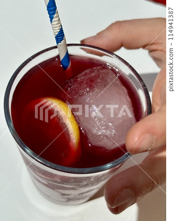 Holding glass of red sangria, Tinto de Verano, top view on white table 114941387