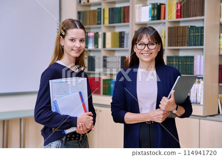 Female teacher and teenage girl high school student looking at camera, in library 114941720