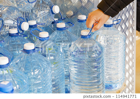 A person is extending their hand to grab a bottle of refreshing water A person is extending their hand to grab a bottle of refreshing water 114941771