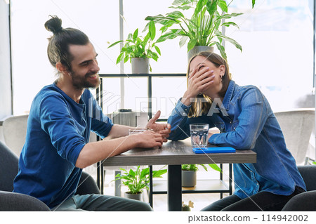 Laughing cheerful young couple sitting together in cafe Laughing cheerful young couple sitting together in cafe 114942002
