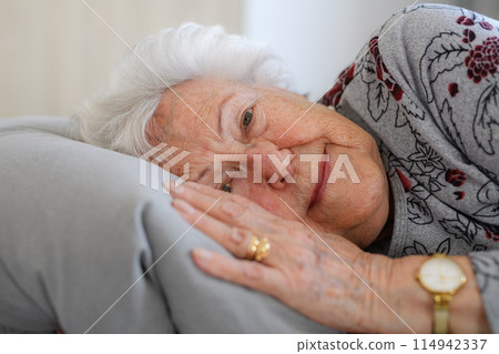 Senior woman lying in her bed alone, feeling anxious. Loneliness, social isolation of eldery woman. Senior woman lying in her bed alone, feeling anxious. Loneliness, social isolation of eldery woman. 114942337