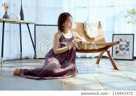 A woman relaxing in a chair in a room 114943372