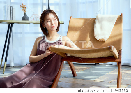 一個女人在房間的椅子上放鬆 一個女人在房間的椅子上放鬆 114943380