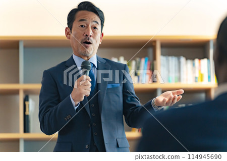 A middle-aged man giving a speech in the lobby 114945690