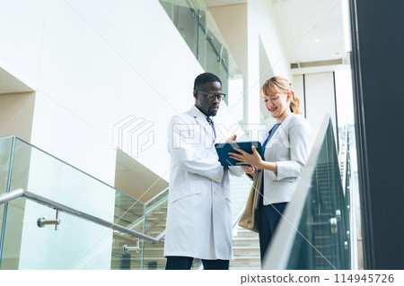 一位研究員和一位身穿白大褂的女商人在辦公室交談 114945726