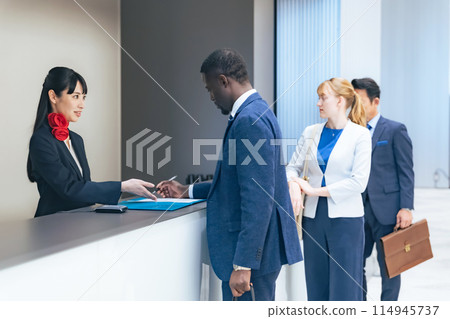 Multinational people checking in at a hotel front desk 114945737