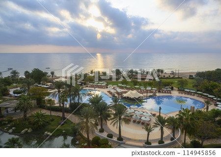 Palm trees, pools and gazebos on beach at dawn on coast of Gulf of Oman in the United Arab Emirates 114945856