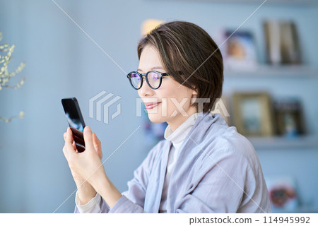 A woman who operates a smartphone in a room A woman who operates a smartphone in a room 114945992