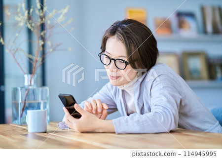 A woman who operates a smartphone in a room A woman who operates a smartphone in a room 114945995