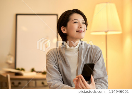 A woman who operates a smartphone in a room 114946001