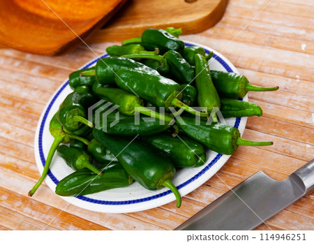 Plate of fresh padron peppers and knife on wooden table Plate of fresh padron peppers and knife on wooden table 114946251