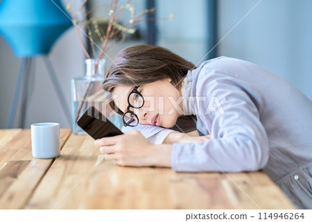 A tired woman operating a smartphone A tired woman operating a smartphone 114946264