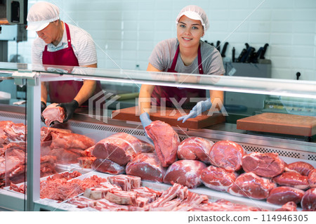 Young female butcher showing raw veal loin slices in butchery 114946305