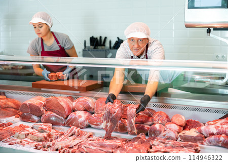 Male farmer of meat products in butcher shop offers to buy fresh beef tenderloin. 114946322