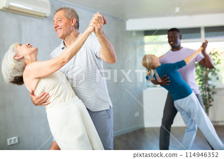 Mature men and women practicing Ballroom dances in training room Mature men and women practicing Ballroom dances in training room 114946352