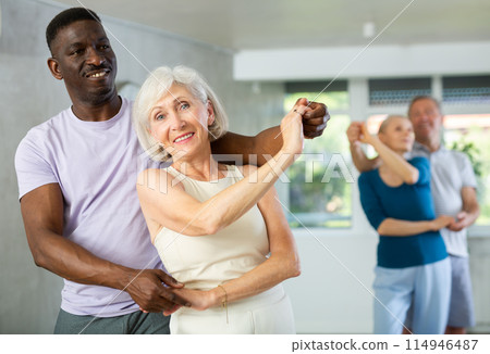 Mature men and women practicing Ballroom dances in training room Mature men and women practicing Ballroom dances in training room 114946487