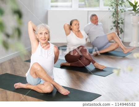 Group of elderly people doing pilates on mat in studio Group of elderly people doing pilates on mat in studio 114946582