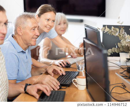 Woman teacher helping elderly people learn how to use computer Woman teacher helping elderly people learn how to use computer 114946712