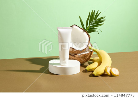 Cosmetic advertising mock up with a white unbranded tube of cosmetic which has banana and coconut as the main ingredient, displayed on a round pedestal, space for adding text or design elements Cosmetic advertising mock up with a white unbranded tube of cosmetic which has banana and coconut as the main ingredient, displayed on a round pedestal, space for adding text or design elements 114947773