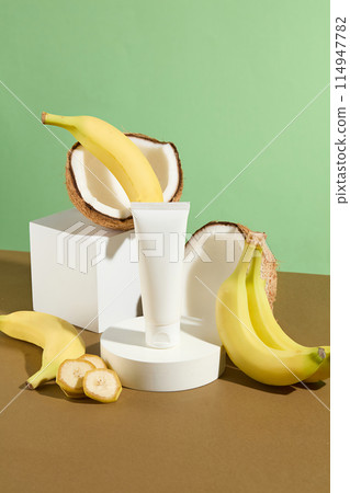 The white blank pedestals in different geometries featured on brown table top with banana and coconut ingredient concept and a unlabeled cosmetic tube for adding brand name, cosmetic advertising The white blank pedestals in different geometries featured on brown table top with banana and coconut ingredient concept and a unlabeled cosmetic tube for adding brand name, cosmetic advertising 114947782