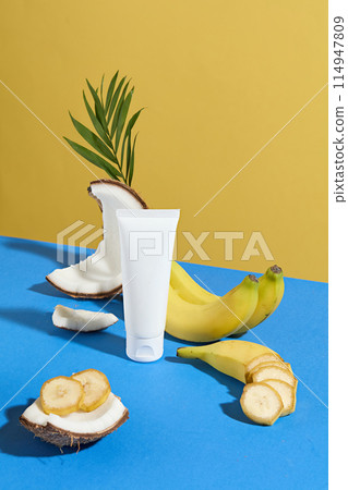 Scene of banana and coconut theme in tropical colorful layout, in front as a coconut piece with some slices of banana above, unlabeled tube of cosmetic in white color, yellow background 114947809