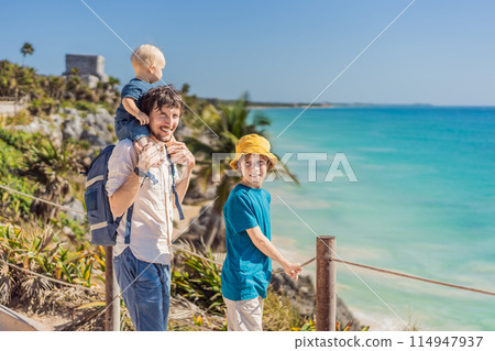 Father and two sons tourists enjoying the view Pre-Columbian Mayan walled city of Tulum, Quintana Roo, Mexico, North America, Tulum, Mexico. El Castillo - castle the Mayan city of Tulum main temple Father and two sons tourists enjoying the view Pre-Columbian Mayan walled city of Tulum, Quintana Roo, Mexico, North America, Tulum, Mexico. El Castillo - castle the Mayan city of Tulum main temple 114947937