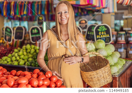 A pregnant woman is at a fruit stand in a grocery store Pregnant woman buying organic vegetables and fruits at Mexican style farmers market 114949185