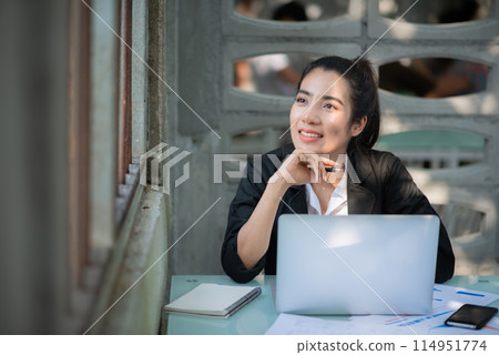 Businesswoman uses smartphone to share internet connection to work on laptop at coffee shop 114951774