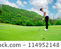 Golfer is using a putter to put a golf ball on the green. 114952148