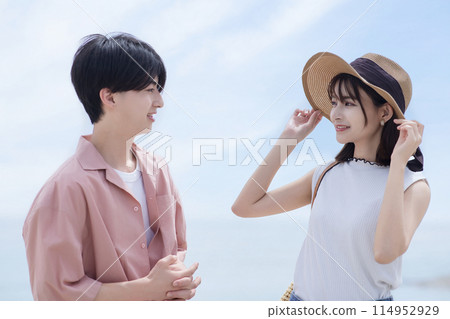 A young couple walking along the beach 114952929
