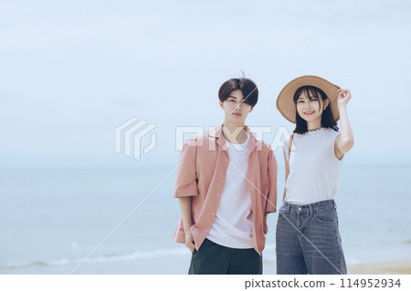 A young couple walking along the beach 114952934