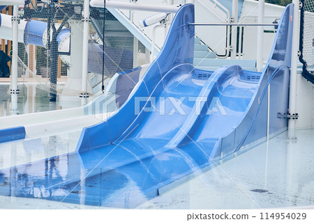 A water park, a bright blue slide with a swimming pool. A water park without people on a summer afternoon in the morning with space to copy. High quality photo A water park, a bright blue slide with a swimming pool. A water park without people on a summer afternoon in the morning with space to copy. High quality photo 114954029
