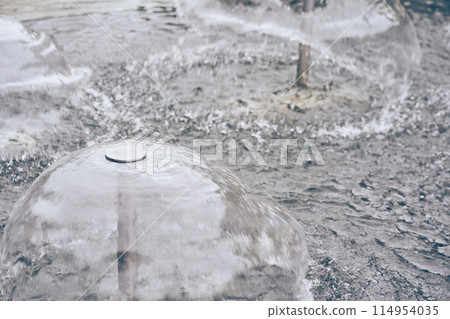 A metal structure in the center of which transparent water forms a small fountain. The jets of water diverge to the sides, creating an effect of serenity. With space to copy. High quality photo 114954035