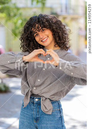 Young woman makes symbol of love, showing heart sign to camera, express romantic positive feelings 114954259