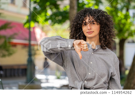 Upset Caucasian woman showing thumbs down sign, disapproval, dissatisfied bad work, mistake in city 114954262