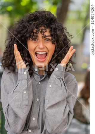 Young woman looking surprised at camera shocked by sudden win good victory news, wow in city street Young woman looking surprised at camera shocked by sudden win good victory news, wow in city street 114954264