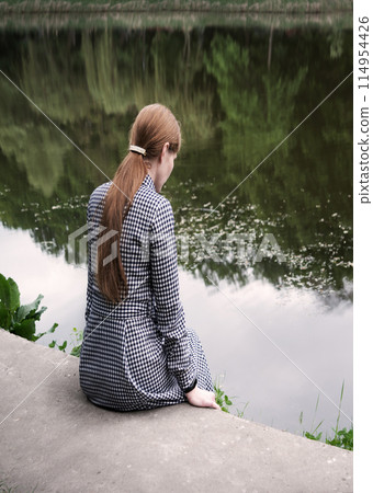 Pretty girl sitting at the lake 114954426