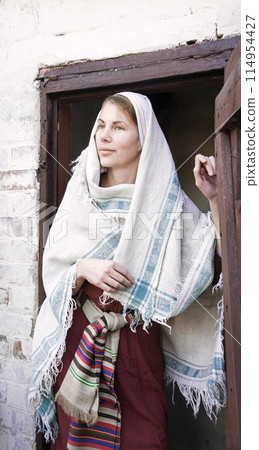 A woman in ancient clothes is standing at the door A woman in ancient clothes is standing at the door 114954427