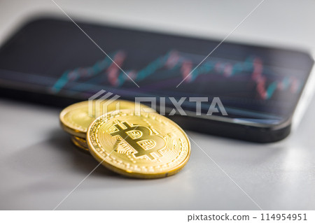 Bitcoin gold coin on gray background. Cryptocurrency and business chart in cellphone. Bitcoin gold coin on gray background. Cryptocurrency and business chart in cellphone. 114954951